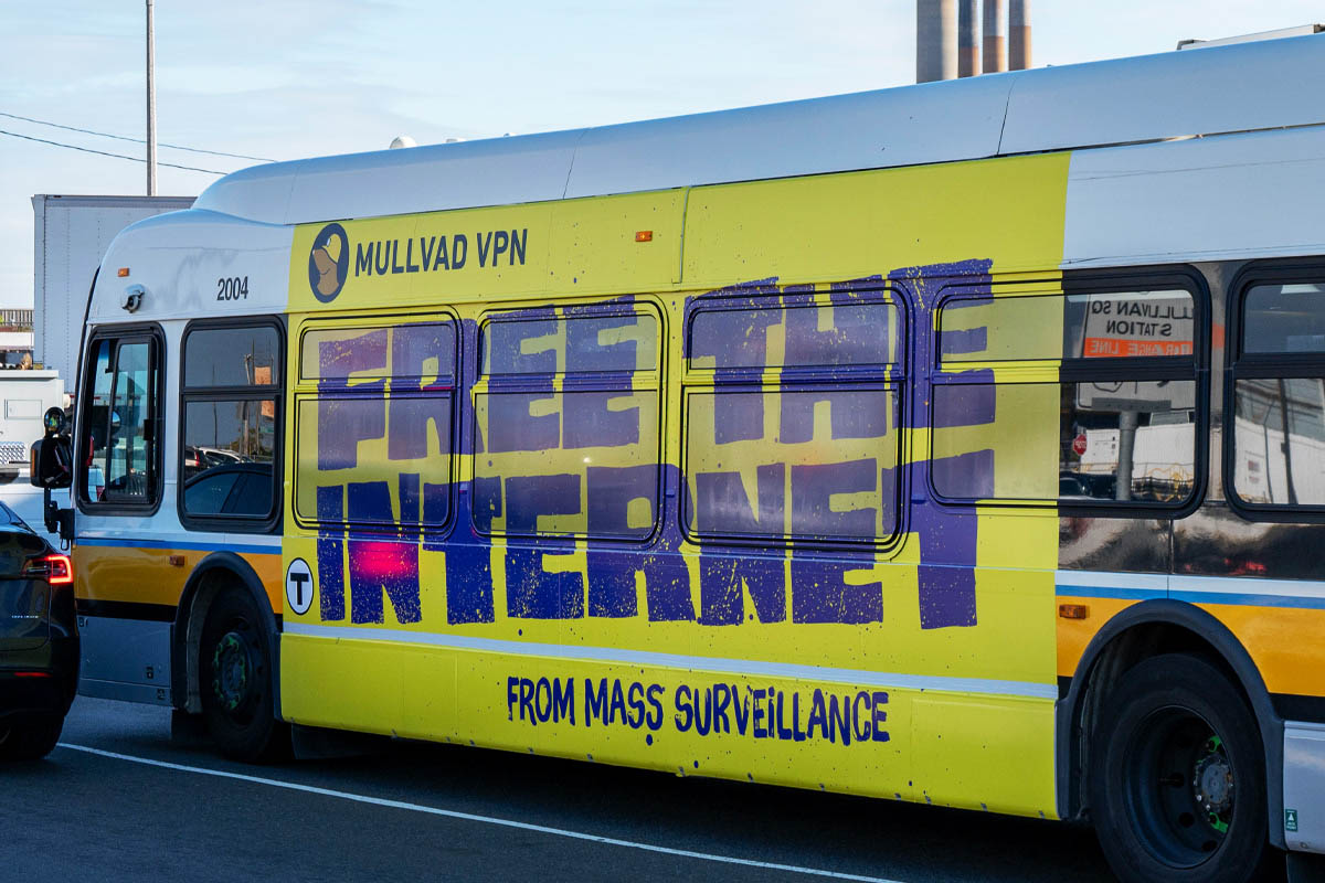 Mullvad VPN bus advertisement with yellow wrap and purple text: FREE THE INTERNET FROM MASS SURVEILLANCE.